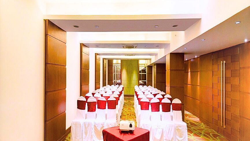A long shot of conference room at Pride Plaza Ahmedabad, featuring rows of chairs with red covers, suitable for seminars or large presentations.